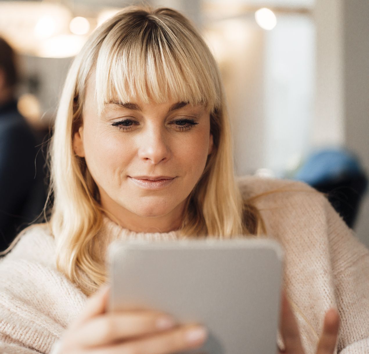 Blonde Frau am Tablet – Symbolfoto für die Nutzung der Zusammen.de Plattform.